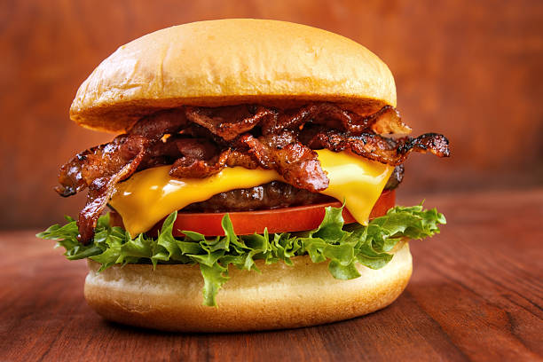 Bacon burger with beef patty on red wooden table